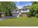 Split-level home featuring a two-car garage, brick accents, and a lush green lawn surrounded by trees at 3929 Emerald Springs Ct, Decatur, GA 30035