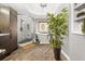 Bright bathroom with herringbone floors, glass shower, soaking tub and leafy green plant at 1008 Stream Valley Ct, Alpharetta, GA 30022