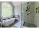 Bathroom featuring standalone tub, shower with glass door, and large window for natural light at 10610 Kingsmark Trl, Alpharetta, GA 30022