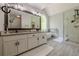 Bright bathroom with double vanity, free-standing tub beneath arch window, and glass-enclosed tiled shower at 10610 Kingsmark Trl, Alpharetta, GA 30022