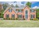 Charming brick home with a manicured lawn, dark shutters, and beautiful landscaping for great curb appeal at 10610 Kingsmark Trl, Alpharetta, GA 30022