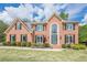 Stunning two-story brick home featuring a manicured lawn, beautiful landscaping and a modern front door at 10610 Kingsmark Trl, Alpharetta, GA 30022
