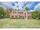 Beautiful two-story brick home featuring manicured lawn, lush landscaping, and a basketball court to the side at 10610 Kingsmark Trl, Alpharetta, GA 30022