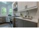 Close-up of the kitchen with marble countertops, white backsplash, stainless steel appliances, and gray lower cabinets at 10610 Kingsmark Trl, Alpharetta, GA 30022