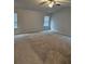 Large bedroom featuring neutral carpeting, two windows with blinds, and a ceiling fan with light fixture at 221 Eleanora Way, Loganville, GA 30052