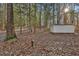 View of a white storage shed and wood pile surrounded by trees and foliage on the property at 337 Andrew Bailey Rd, Sharpsburg, GA 30277