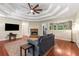 Living room with hardwood floors, stone fireplace, tray ceiling, and seamless flow to dining area at 588 Peachtree Se Dr, White, GA 30184