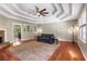 Spacious living room featuring hardwood floors, a stone fireplace, and an elegant tray ceiling with fan at 588 Peachtree Se Dr, White, GA 30184