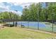 Well-maintained tennis court with a black fence, surrounded by mature trees and grassy areas at 1545 Center Cross Pass, Marietta, GA 30062