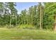View of green grass area and wooded backyard with brick border in a residential neighborhood at 194 Jennifer Nw Ln, Lilburn, GA 30047