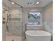 Bathroom featuring walk-in shower with marble-style tiling, a large tub, and chrome fixtures at 194 Jennifer Nw Ln, Lilburn, GA 30047