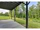 View of covered patio area with green grass, wooded backyard, and black support beams at 194 Jennifer Nw Ln, Lilburn, GA 30047