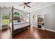 Bright main bedroom with hardwood floors, arched window, ceiling fan, and canopy bed at 47 Centerport Dr, White, GA 30184