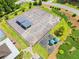 Aerial view of fenced tennis court with covered benches plus playground, lush lawns and green foliage surround the property at 47 Centerport Dr, White, GA 30184