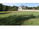 Spacious backyard with lush green grass and wooden fence surrounded by trees and gazebo in the background at 1699 Little Fox Ln, Dacula, GA 30019