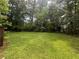 Expansive, verdant backyard surrounded by mature trees, offering ample space for recreation and outdoor enjoyment at 4135 Moore Rd, Conley, GA 30288
