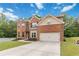 Two-story brick home featuring an attached garage, lush landscaping, and a spacious driveway at 1934 Acorn Ln, Dacula, GA 30019