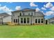 Backyard of a brick home features large windows and a wooden deck, perfect for outdoor entertaining at 11305 Knollwood Bend, Johns Creek, GA 30097