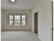 A bright bedroom with neutral carpeting and walls and triple windows overlooking the neighborhood at 11305 Knollwood Bend, Johns Creek, GA 30097