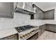 Modern kitchen showcasing a stainless steel range hood over a gas cooktop and gray cabinets and quartz countertops at 11305 Knollwood Bend, Johns Creek, GA 30097