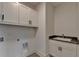 The well-lit laundry room features white cabinets, a sink and dark countertop and patterned tile flooring at 11305 Knollwood Bend, Johns Creek, GA 30097