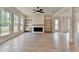 Open-concept living room with fireplace, built-in shelves, and a view to the backyard through a bank of windows at 11305 Knollwood Bend, Johns Creek, GA 30097