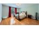 Bedroom with a large window with red curtains, a bed with a decorative metal frame, and hardwood floors at 1025 Ector Nw Dr, Kennesaw, GA 30152