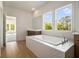 Bathroom featuring a soaking tub with tile surround and large windows providing lots of natural light at 4039 Tallow Pl, Woodstock, GA 30188