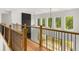 Second-floor hallway with wood and iron railing overlooking the living room with abundant natural light at 4039 Tallow Pl, Woodstock, GA 30188