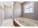 Bathroom featuring a soaking tub, white tile flooring, and neutral patterned wallpaper at 1366 Maple Ridge Dr, Suwanee, GA 30024
