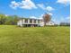 Expansive backyard featuring a white home with black trim and mature trees on a lush green lawn under a partly cloudy sky at 1871 Weems Rd, Locust Grove, GA 30248