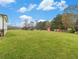 Wide-open backyard showing a playground, storage building, and fencing amidst green grass and distant trees at 1871 Weems Rd, Locust Grove, GA 30248