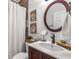 Well-lit bathroom with a dark wood vanity, white countertop, round mirror, and decorative wall art at 3675 Peachtree Ne Rd # 9, Atlanta, GA 30319