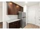 Kitchen featuring stainless steel refrigerator, granite countertops, and dark wood cabinets at 11112 Benton Woods Dr, Covington, GA 30014