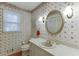 Cozy bathroom featuring floral wallpaper, a bright vanity, and an oval mirror at 4092 Deerbrook Sw Way, Lilburn, GA 30047