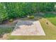 Private basketball court in a wooded area with a concrete surface surrounded by lush grass and landscaping at 630 Silverberry Ln, Sugar Hill, GA 30518
