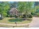Charming brick two-story home with manicured lawn, mature trees, and a circular driveway, showcasing curb appeal at 630 Silverberry Ln, Sugar Hill, GA 30518