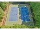 Overhead view of two well-maintained blue tennis courts surrounded by lush green trees in a private setting at 630 Silverberry Ln, Sugar Hill, GA 30518