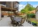 Backyard patio with an outdoor dining table and stairs leading up to a screened porch with string lights at 1212 Overlook Lake Dr, Dacula, GA 30019