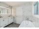 Modern bathroom showcasing marble walls, and freestanding tub near a dual vanity at 1482 Connally Sw Ave, Atlanta, GA 30310