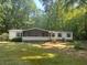 Quaint single-story home with a screened-in porch, surrounded by a lush green lawn and mature trees for privacy at 148 Boogers Hill Rd, Oxford, GA 30054