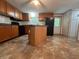 Traditional kitchen features wood cabinets, black appliances, and center island on a tile floor at 148 Boogers Hill Rd, Oxford, GA 30054