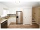Well lit kitchen leads to stairs with stainless refrigerator and granite countertops at 1616 W Kellogg Cir, Douglasville, GA 30134