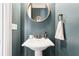 Stylish powder room with a pedestal sink, round mirror, and sophisticated wall color at 2685 Grady Se St, Smyrna, GA 30080