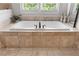Elegant bathroom featuring a tiled bathtub with sleek fixtures and natural light from the window at 2685 Grady Se St, Smyrna, GA 30080