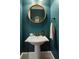 Stylish powder room featuring a pedestal sink, and round mirror with teal colored walls at 2685 Grady Se St, Smyrna, GA 30080