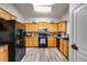 Well-equipped kitchen featuring wood cabinetry, black appliances, and modern vinyl flooring at 5069 Luxford Dr, Douglasville, GA 30135
