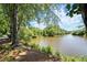 Scenic view of a serene lake surrounded by lush greenery and mature trees, creating a peaceful natural setting at 5626 River Heights Se Xing, Marietta, GA 30067