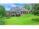Spacious backyard featuring a large lawn and exterior of a brick home with covered patio at 6515 Ashbourne Ct, Suwanee, GA 30024