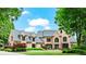Impressive brick home featuring manicured landscaping, a large lawn, and architectural roof lines at 6515 Ashbourne Ct, Suwanee, GA 30024